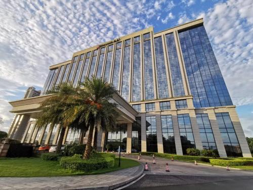 a building with a palm tree in front of it at HUALUXE Yangjiang City Center in Yangjiang