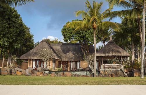 atropical house with a palm tree in front of it at Shanti Maurice Resort & Spa in Bel Ombre