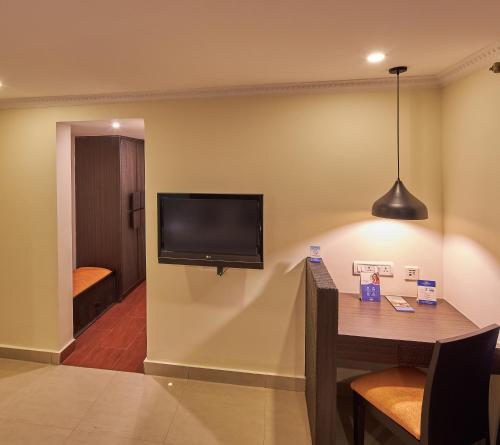 a room with a tv on a wall with a table at Tulip Inn Koramangala Bangalore in Bengaluru