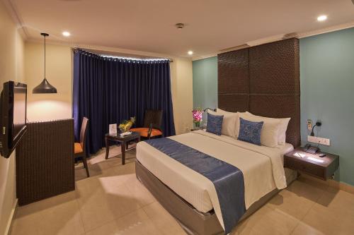 a bedroom with a large bed and a room with a desk at Tulip Inn Koramangala Bangalore in Bengaluru
