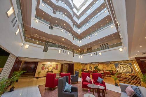 a hotel lobby with red chairs and a skylight at Tulip Inn Koramangala Bangalore in Bengaluru