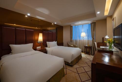 a hotel room with two beds and a desk at Chengdu Tianfu Sunshine Hotel in Chengdu