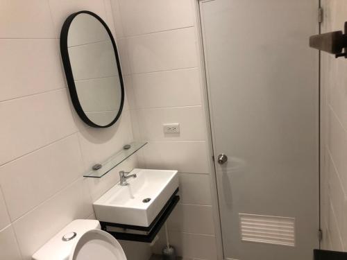 a white bathroom with a sink and a mirror at Rolling Pin Homestay in Tainan
