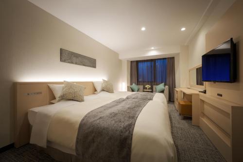 盛岡市にあるホテルロイヤル盛岡の大型ベッド1台、薄型テレビが備わるホテルルームです。