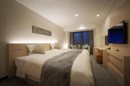 a hotel room with a large bed and a flat screen tv at Hotel Royal Morioka in Morioka