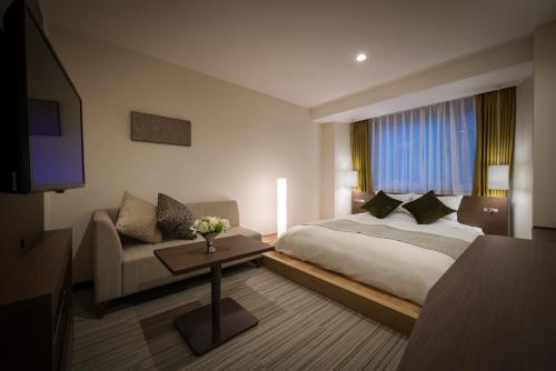 a hotel room with a bed and a couch at Hotel Royal Morioka in Morioka