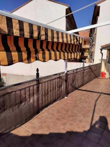 a fence with a striped umbrella on a sidewalk at Apartamentos El Mirador in Candeleda