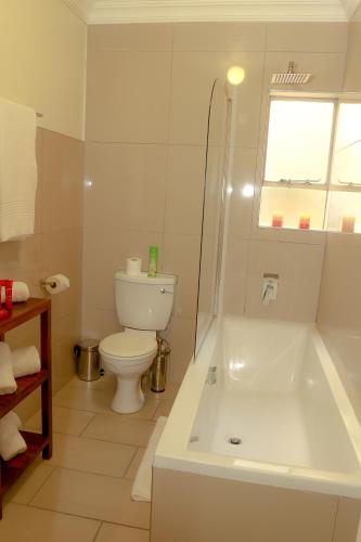 a white bathroom with a tub and a toilet at Hotel @ Tzaneen in Tzaneen