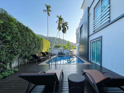 a deck with chairs and a swimming pool at Purepamvillage in Kata Beach