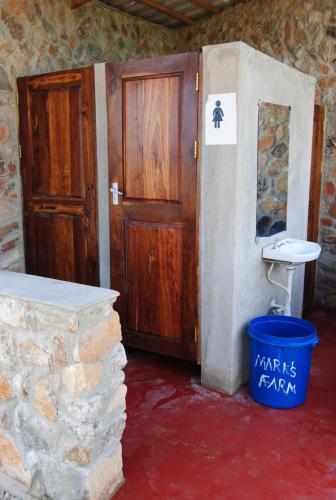 a bathroom with a toilet and a wooden door at MARK's farm & ecolodge in Kalenga