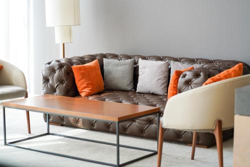 a living room with a brown couch with orange pillows at IntercityHotel Dubai Jaddaf Waterfront in Dubai