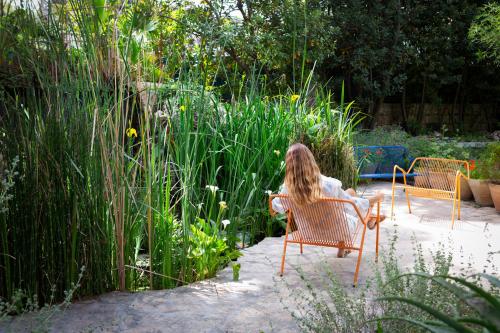 a woman sitting in a chair in a garden at The American Colony Hotel - Small Luxury Hotels of the World in Jerusalem