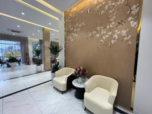 a lobby with two chairs and a wall with flowers at Mango Hotel - Ha Noi Railway station in Hanoi