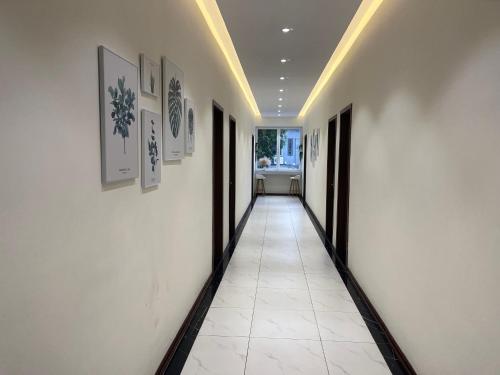 a hallway with white walls and white tile floors at Mango Hotel - Ha Noi Railway station in Hanoi