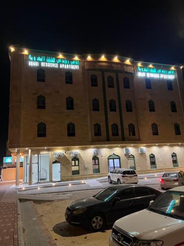 een groot gebouw met auto's geparkeerd voor het bij شقق القارات السبع الاحساء in Al Hofuf
