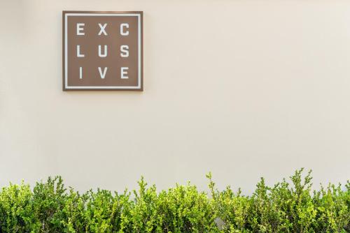 un cartello sul lato di un edificio bianco con cespugli verdi di Hotel & Residence Exclusive a Marina di Carrara