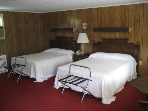 two beds in a hotel room with wood paneling at Fountain View Motel in Richfield Springs