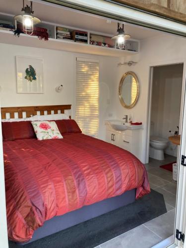a bedroom with a red bed and a bathroom at The Treehut in Ohauiti