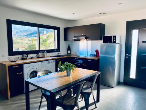 a kitchen with a table and a refrigerator at T2 Loft entre mer et montagne in Calenzana