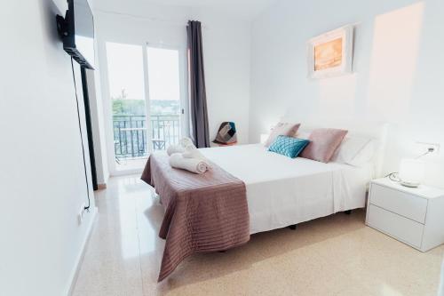 um quarto com uma cama branca e uma grande janela em Hostal Noray em Punta Prima