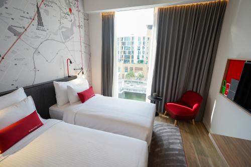 a hotel room with two beds and a red chair at IntercityHotel Dubai Jaddaf Waterfront in Dubai