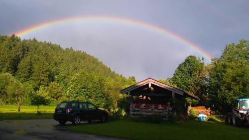 een regenboog in de lucht boven een huis met een vrachtwagen bij Haus Bamberger in Fischbachau