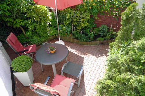 eine Terrasse mit einem Tisch, Stühlen und einem Sonnenschirm in der Unterkunft Ferienhaus der kurzen Wege Objekt 40105 in Warnemünde
