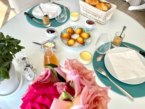 een witte tafel met borden met eten en bloemen erop bij Villa de la Croix in Villechétif