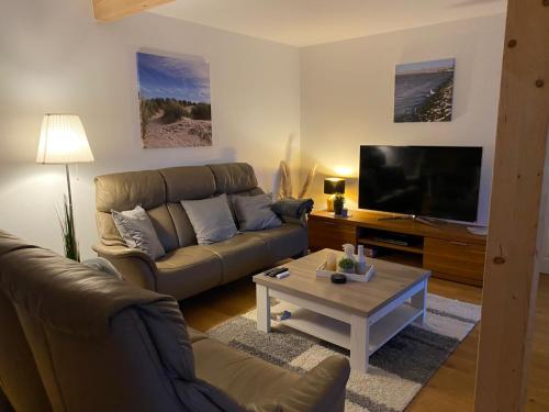 uma sala de estar com um sofá e uma televisão em Landhaus "Alte Welt" Nordseeküste em Osteel