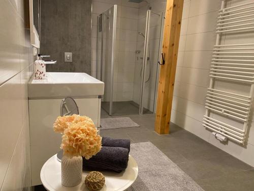baño con lavabo, ducha y jarrón con flores en Landhaus "Alte Welt" Nordseeküste, en Osteel