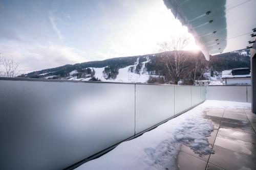 a snow covered balcony with a view of a mountain at Das Conrad by Schladming-Appartements in Schladming