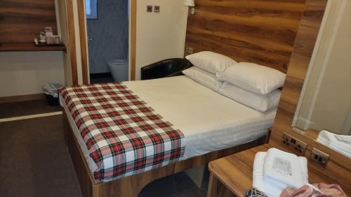 a small bedroom with a bed and a mirror at Hampton Court Guesthouse - City Centre in Glasgow