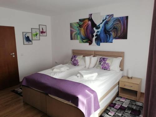 a bedroom with a bed with a painting on the wall at Happy House in Hunedoara