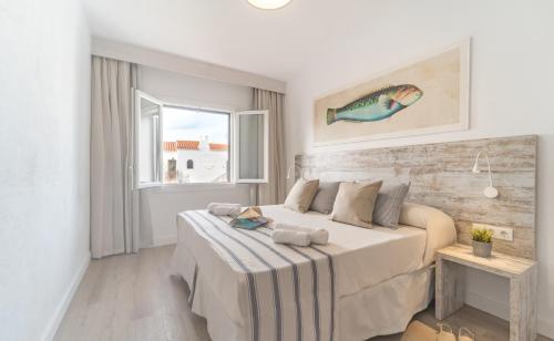 a white bedroom with a bed and a window at FERGUS Club Carema Splash in Fornells
