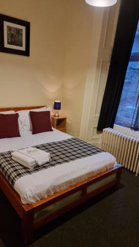 a bedroom with a large bed with a window at Hampton Court Guesthouse - City Centre in Glasgow
