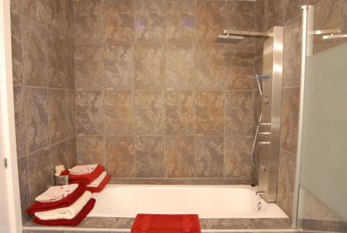 a bathroom with a shower and a tub with red towels at Go Donosti Villa Buda in San Sebastián