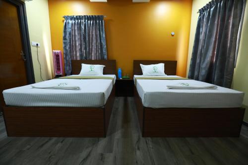 two beds sitting next to each other in a room at The Ideal Nest Kumbakonam in Kumbakonam