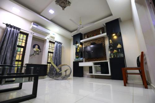 a living room with a tv on a wall at The Ideal Nest Kumbakonam in Kumbakonam