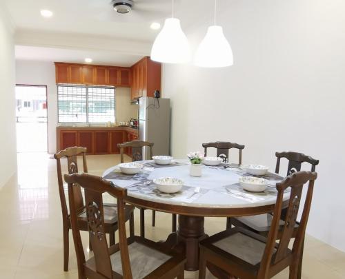 a dining room table with four chairs and a kitchen at NanSang One Homestay 8pax 4Rooms in Sibu