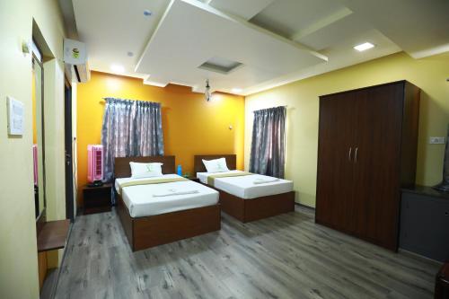 a room with two beds and a cabinet in it at The Ideal Nest Kumbakonam in Kumbakonam