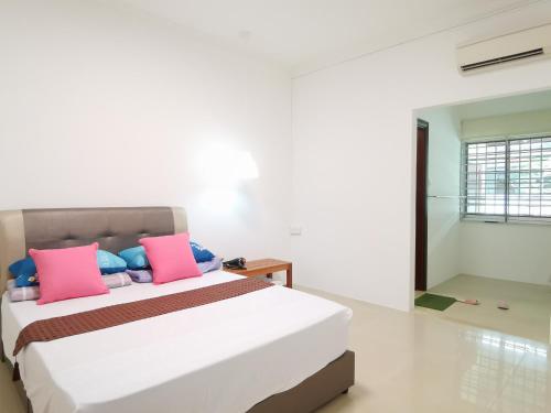 1 dormitorio con 1 cama con almohadas rosas y azules en NanSang One Homestay 8pax 4Rooms, en Sibu