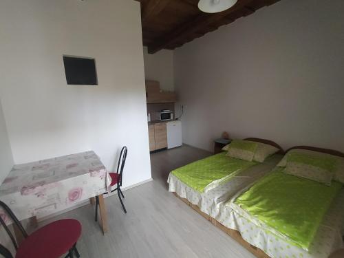 a bedroom with a bed and a table and a kitchen at Heni Vendégháza in Vadna