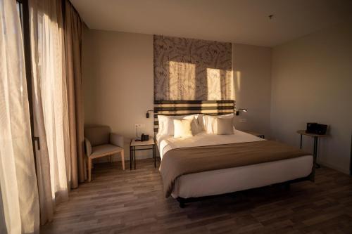 a hotel room with a bed and a chair at abba Sevilla in Seville