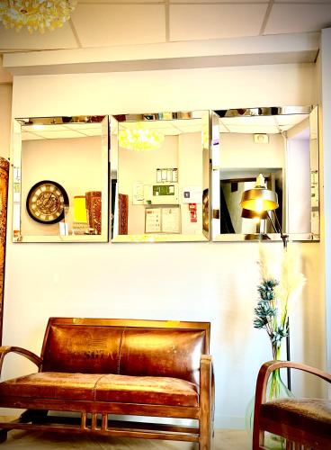 a brown leather couch against a wall with mirrors at Hôtel Paul Riquet in Béziers