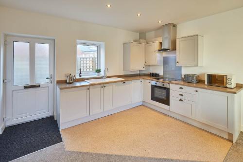 a large kitchen with white cabinets and a window at Host & Stay - West Cliff Retreat in Whitby