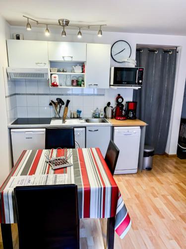 une cuisine avec une table avec des chaises et un micro-ondes dans l'établissement Appartement*** T2 + cabine pour 4 personnes, à Cauterets