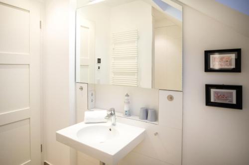 a white bathroom with a sink and a mirror at Ostsee - Appartement Nr 19 "Sonnenzauber" im Strand Resort in Heiligenhafen