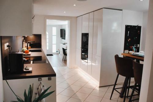 uma cozinha com armários brancos e uma mesa e cadeiras em Smart-Apartment BlickWinkel Schwarzwald em Gaggenau