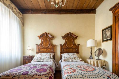 a bedroom with two twin beds and a chandelier at Palazzo Benassi Penthouse in Asolo