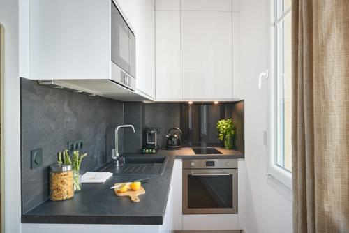 une cuisine avec des armoires blanches et un comptoir noir dans l'établissement Sunlight Properties - Daffia - Beautifully renovated studio, city pad in Central Nice, à Nice